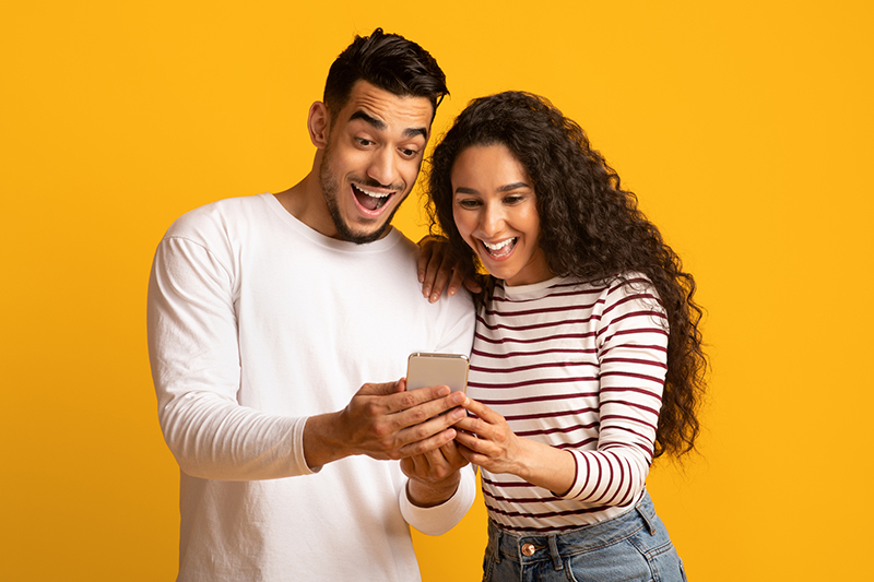 Cool App. Excited arab couple looking at smartphone screen in hands